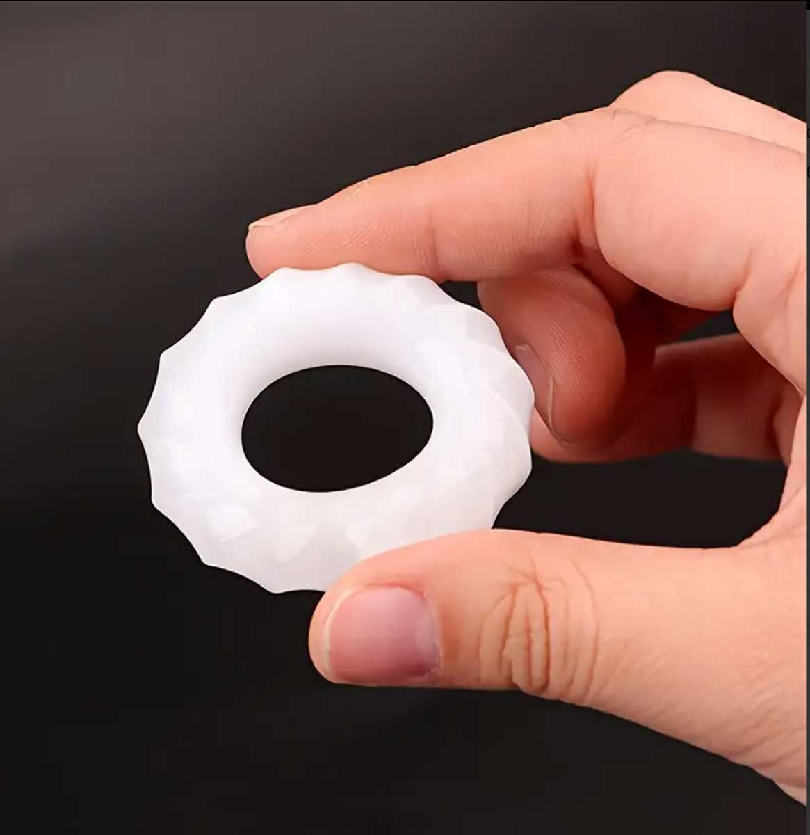 Прозоре силіконове ерекційне кільце з рельєфними ребрами на білому фоні